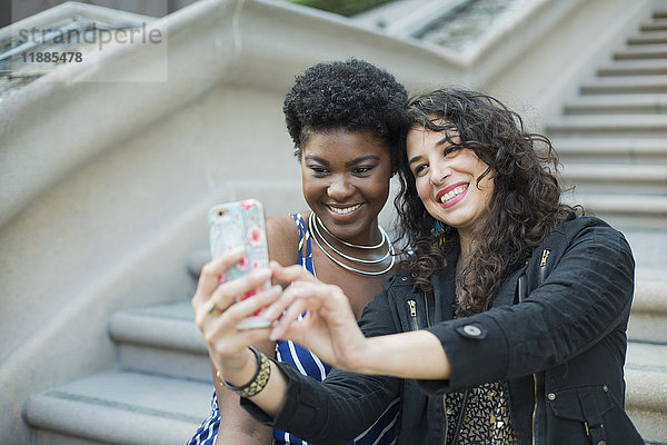 Glückliche Frau nimmt Selfie mit junger Freundin gegen Schritte