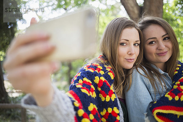 Zärtliche weibliche Freunde  die Selfie durch Smartphone im Park nehmen