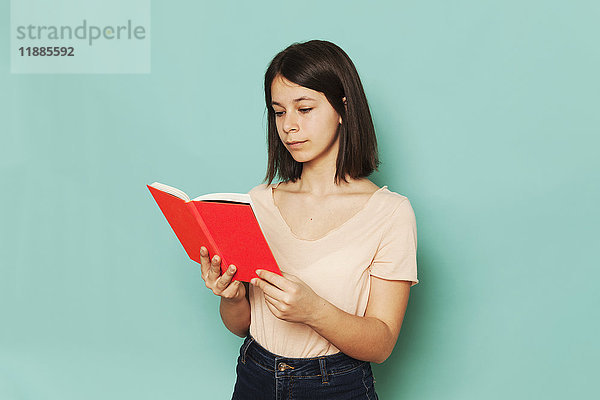 Mädchen lesen Roman vor türkisfarbenem Hintergrund