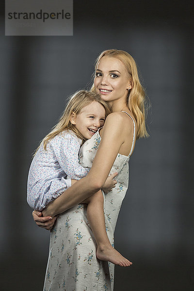 Seitenansicht Porträt der Mutter mit Tochter vor schwarzem Hintergrund