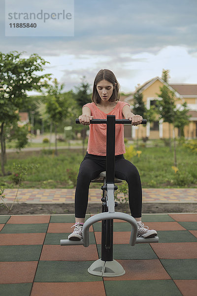 Junge Frau in voller Länge mit Trainingsgeräten im Park