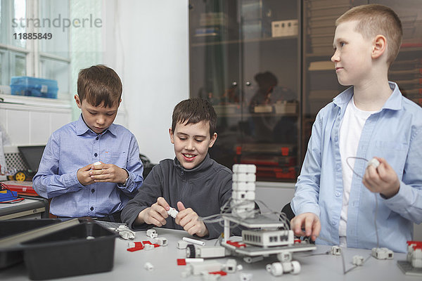Lächelnde Schüler bei der Arbeit am Maschinenteil am Tisch im Klassenzimmer