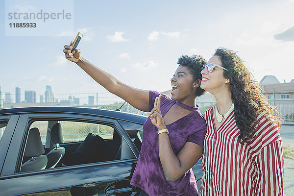 Glückliche junge Frau nimmt Selfie mit Freundin mit dem Auto gegen den Himmel  Los Angeles  Kalifornien  USA