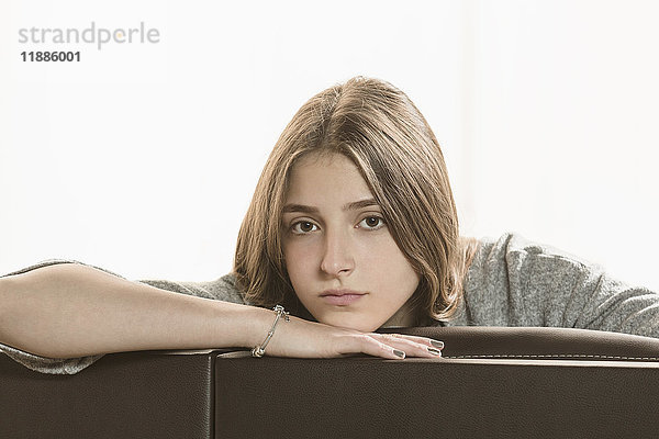 Porträt eines Teenagermädchens auf Sofa vor weißem Hintergrund