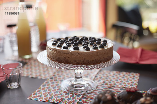 Torte auf Ständer über Platzdeckchen am Tisch während der Party