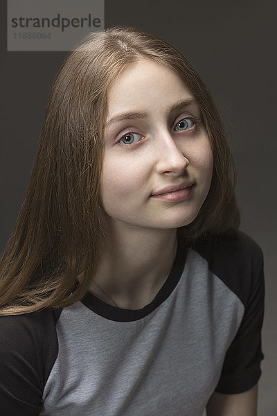 Nahaufnahme eines Mädchens mit langen braunen Haaren vor grauem Hintergrund