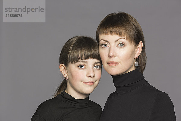 Portrait von Mutter und Tochter mit Rollkragenpulli vor grauem Hintergrund
