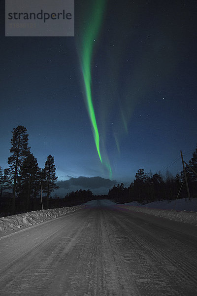 Idyllischer Blick auf Aurora Borealis über schneebedeckte Straße bei Nacht  Kiruna  Schweden