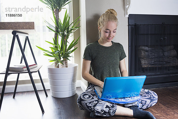 Junge blonde Frau mit Laptop an der Wand zu Hause