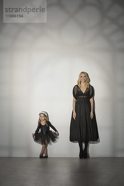 Portrait von Mutter und Tochter in schwarzem Kostüm an der Wand stehend im Tanzstudio