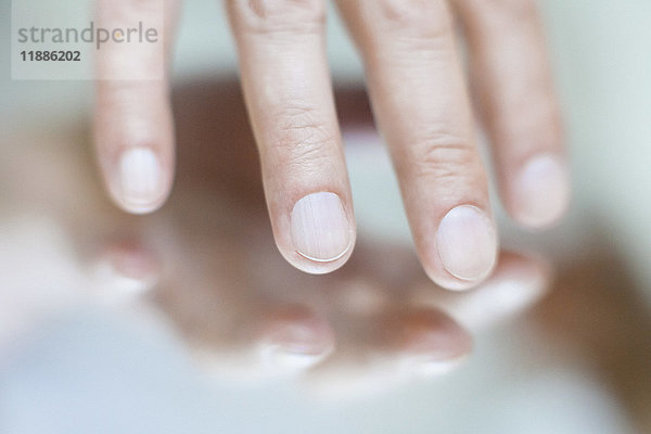 Abgeschnittenes Bild der handberührenden Spiegelfläche