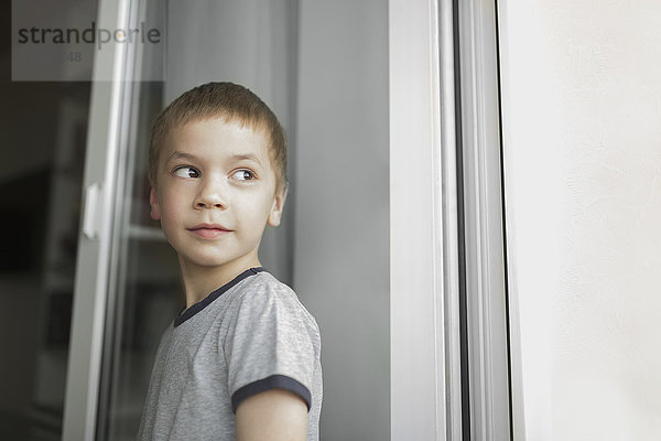 Junge schaut weg  während er an der Wand steht.