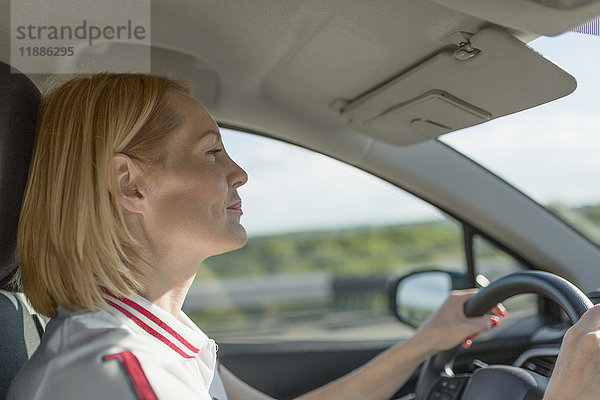 Seitenansicht der selbstbewussten reifen Frau beim Autofahren an einem sonnigen Tag