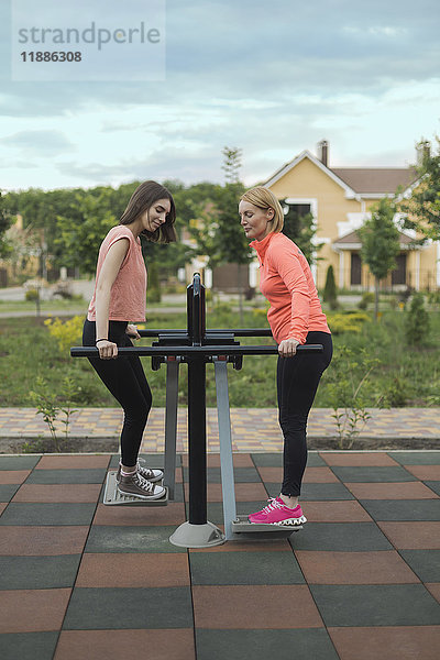 Volle Länge von Mutter und Tochter mit Trainingsgeräten im Park