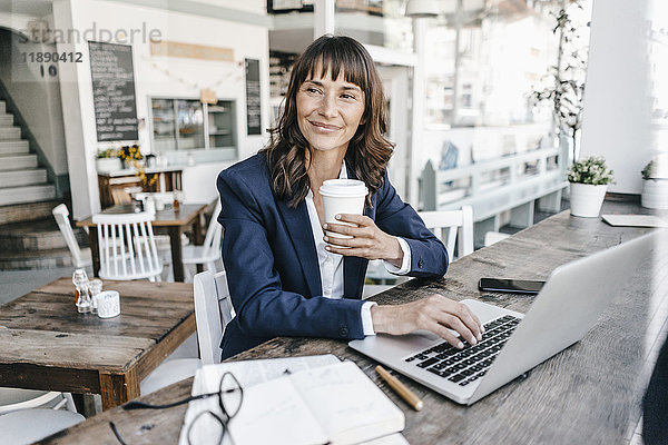 Geschäftsfrau im Café mit Laptop und Kaffee trinken