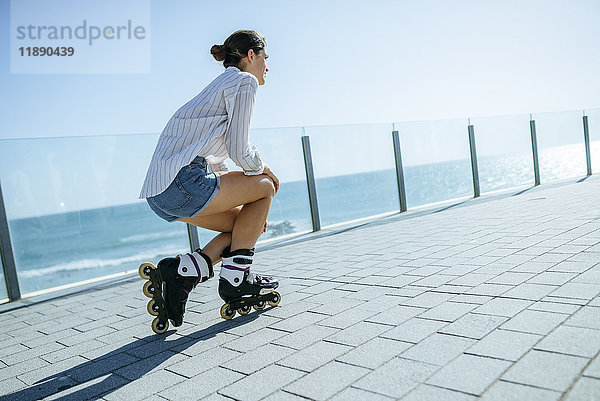Junge Frau mit Inline-Skates auf der Strandpromenade an der Küste