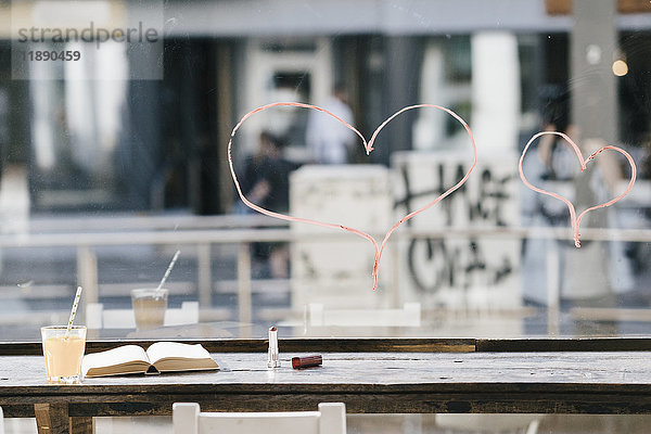 Buchen und trinken im Café mit Lippenstift-Herzen am Fenster