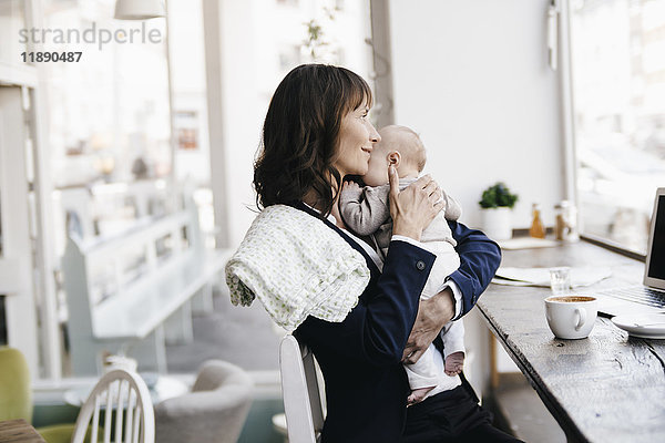 Geschäftsfrau im Café beim Küssen ihres Babys