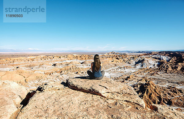 Chile  Atacama-Wüste  Rückansicht der auf einem Felsen sitzenden Frau mit Blick auf die Aussicht