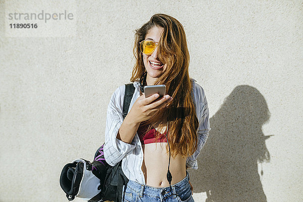 Junge Frau mit Inline-Skates in der Tasche per Handy