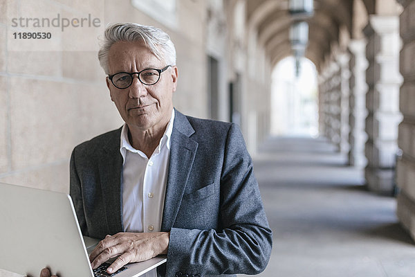 Porträt eines älteren Geschäftsmannes mit Laptop