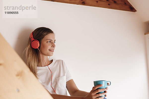 Junge Frau entspannt zu Hause bei einer Tasse Tee  Musik hören