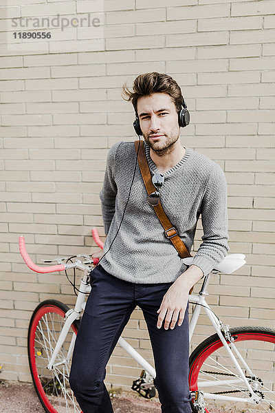 Portrait eines jungen Mannes mit Rennrad und Kopfhörer
