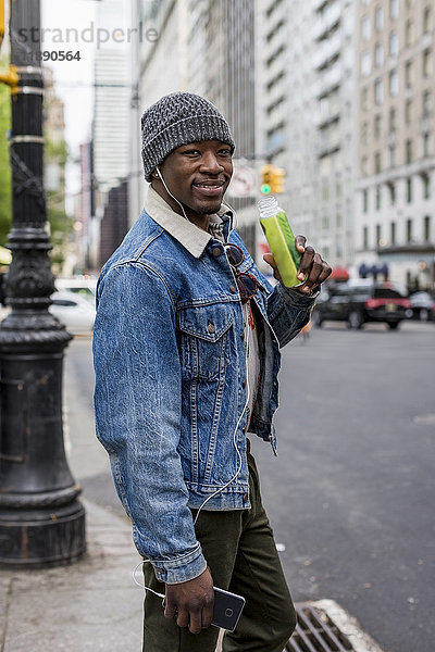 USA  New York City  Manhattan  Portrait eines lächelnden Mannes mit Flasche
