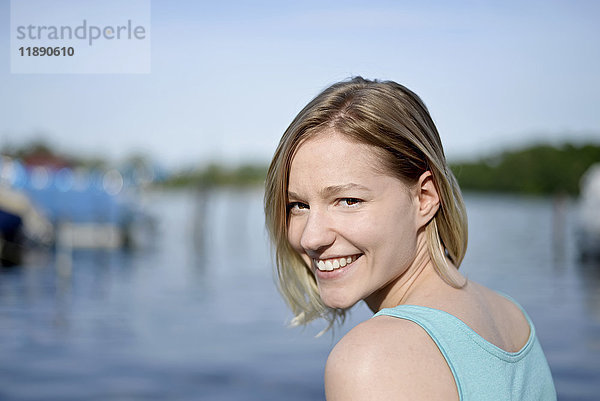 Porträt einer lächelnden jungen Frau vor einem See