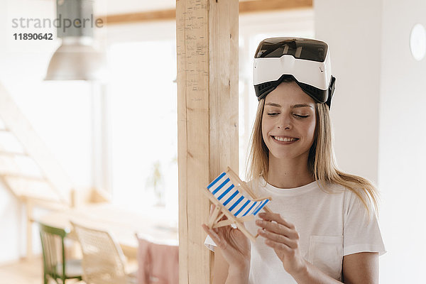 Junge Frau mit VR-Brille  Urlaubsplanung  Spielzeugstuhl in der Hand