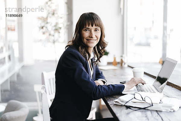 Geschäftsfrau sitzend im Café mit Laptop  lächelnd