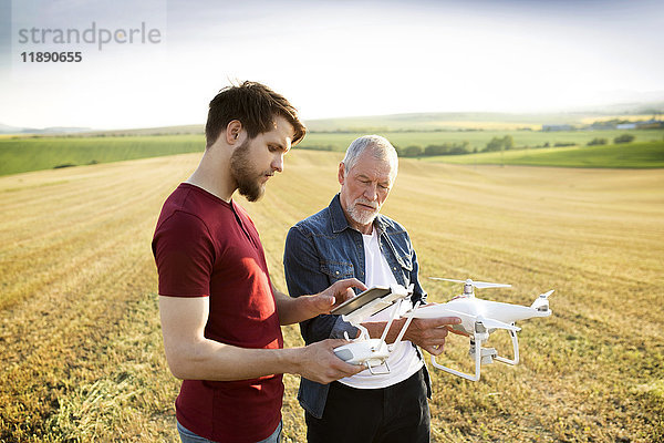 Senior Vater und sein erwachsener Sohn mit Drohne auf einem Feld