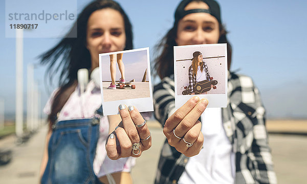 Zwei junge Frauen zeigen Sofortbilder mit ihren Longboards
