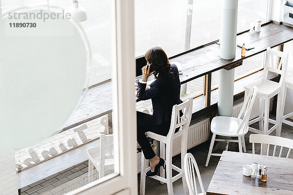 Geschäftsfrau im Café  mit Smartphone und Laptop