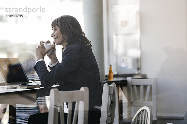 Businesswoamn mit Laptop  im Café sitzen  Kaffee trinken