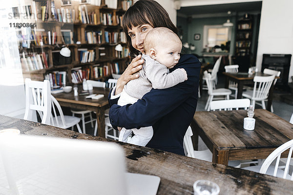 Geschäftsfrau im Cafe hält Baby