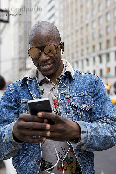 USA  New York City  Manhattan  Porträt eines Mannes mit verspiegelter Sonnenbrille auf dem Handy