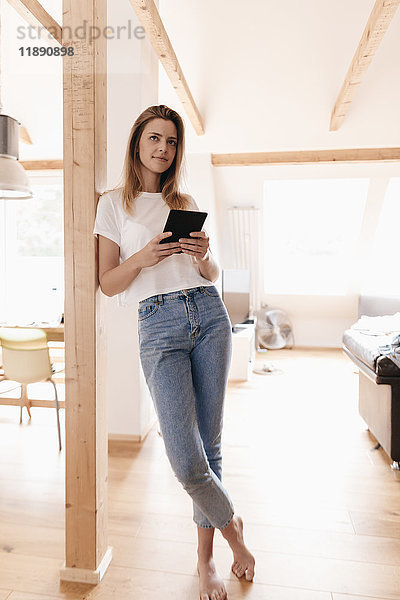 Junge Frau zu Hause mit digitalem Tablett