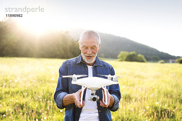 Porträt eines älteren Mannes mit Drohne auf einer Wiese