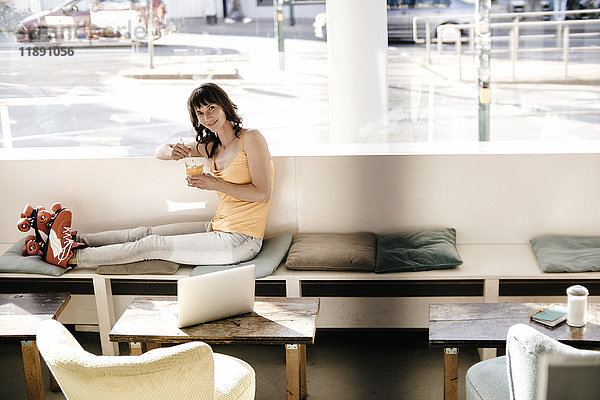 Frau mit Rollschuhen in einem Café sitzend  einen Drink nehmend