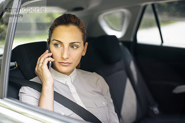 Geschäftsfrau am Telefon sitzend auf dem Rücksitz eines Autos