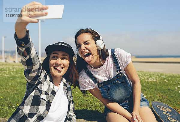 Porträt von zwei jungen Frauen  die sich selbst mit dem Smartphone fotografieren.