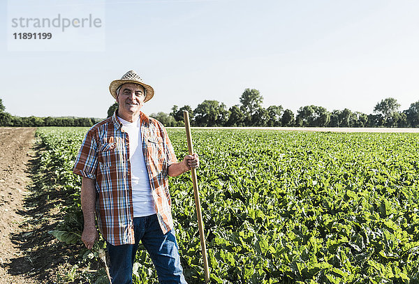 Porträt eines lächelnden älteren Bauern  der vor einem Feld steht.