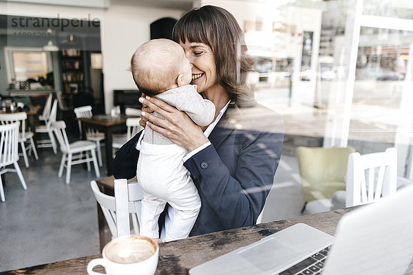 Geschäftsfrau im Cafe hält Baby