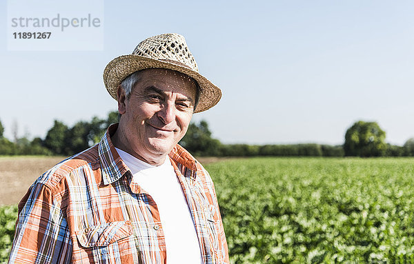 Porträt eines zufriedenen Landwirts  der vor einem Feld steht