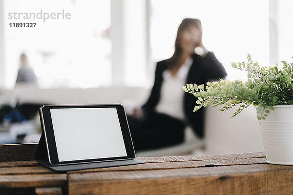 Geschäftsfrau im Café mit digitalem Tablett im Vordergrund