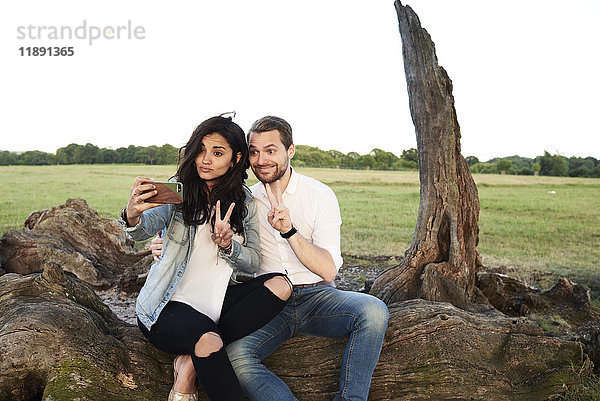 Junges Paar in der Natur nimmt Selfie mit Smartphone zieht lustige Gesichter