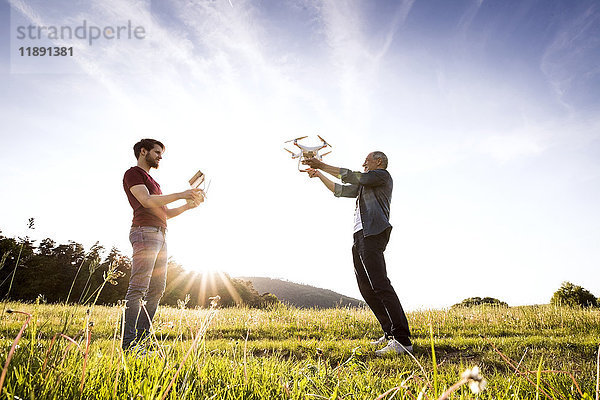 Senior Vater und sein erwachsener Sohn mit Drohne auf einer Wiese