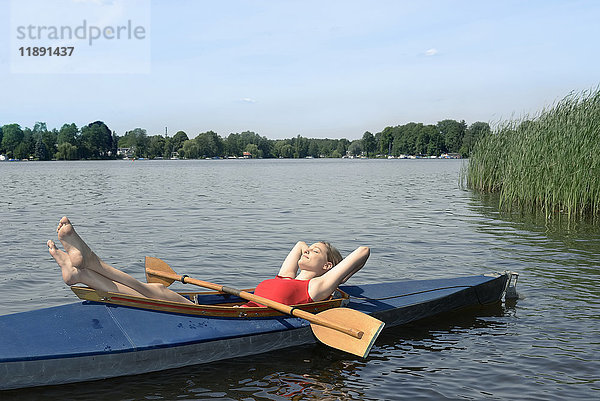 Frau beim Sonnenbaden im Kajak auf einem See