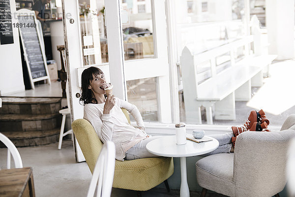 Frau mit Rollschuhen in einem Café sitzend  Eis essend